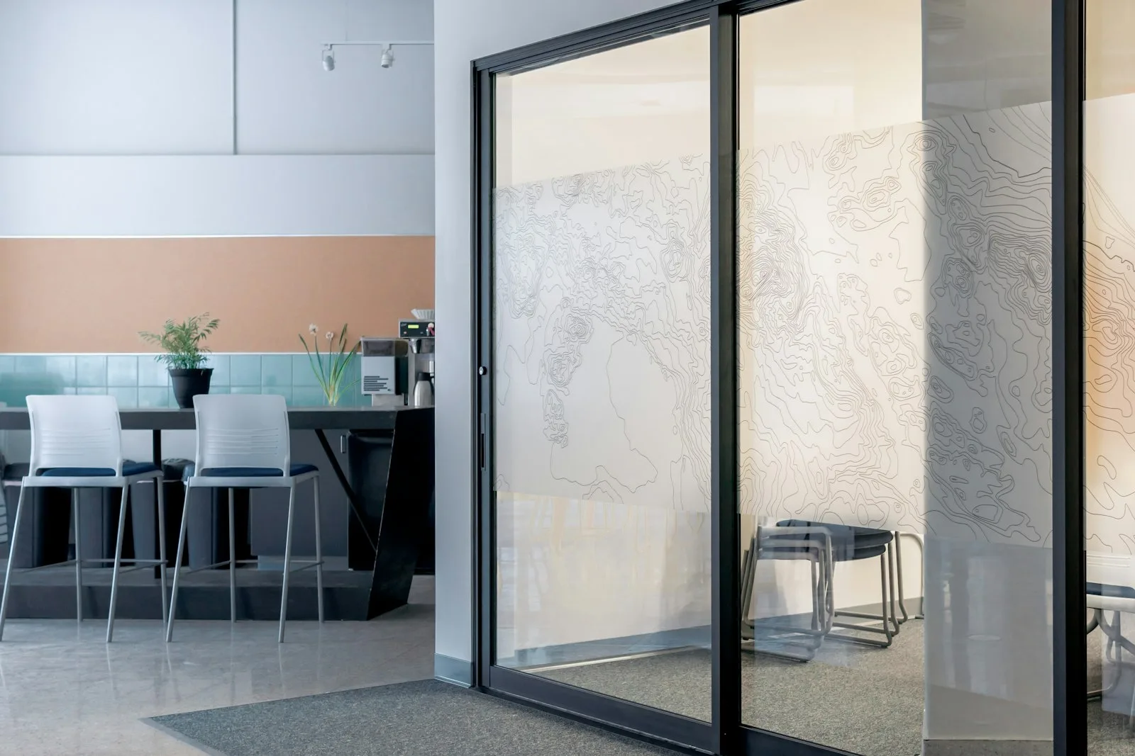 Raumhohe Glasschiebetür als Trennwand in einem hellen Raum
